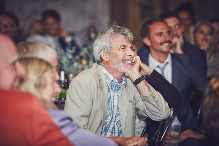guest laughing at wedding speeches at festival style barn wedding in devon