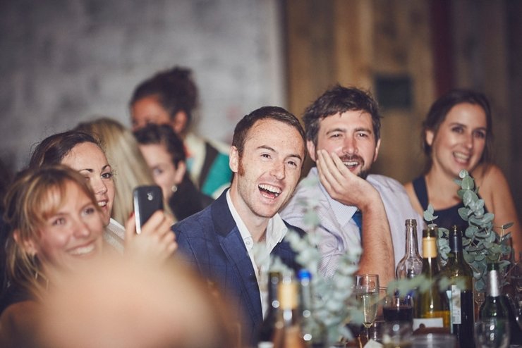 guest laughing at wedding speeches at festival style barn wedding in devon
