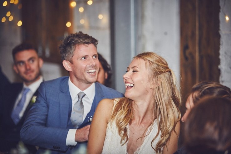 guest laughing at wedding speeches at festival style barn wedding in devon