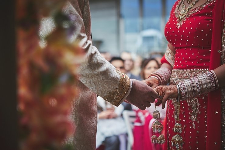 close up of joined hands with henna painting and gold jewellery at modern hindu and Sikh wedding ceremony at Tunnels Beaches in Devon