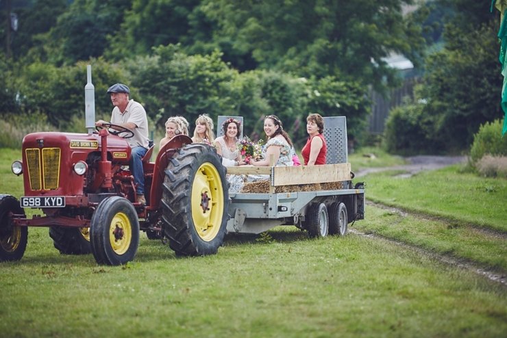 Bridal party arrival to outdoor ceremony on a tractor.jpg